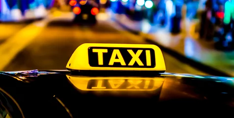 Foto op Plexiglas Night picture of a taxi car. Taxi sign on the car roof glowing in the dark © orelphoto