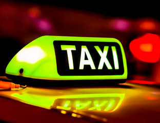 Taxi in the city at the dark. Car with glowing taxi sign moving in the night