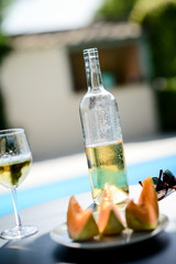 two glass of cool white wine with bottle outdoor in a restaurant pool side terrace in sunny summer day