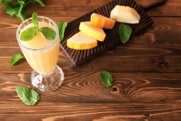 Glass with delicious melon smoothie on wooden table