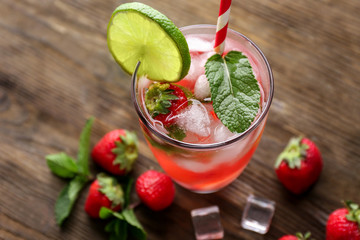 Glass of fresh strawberry mojito on wooden table