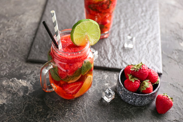 Mason jar of fresh strawberry mojito on grey table