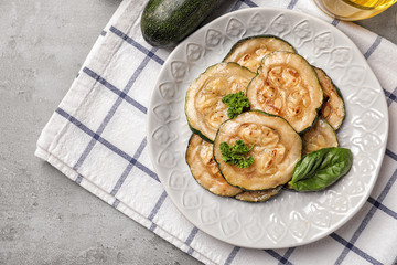 Plate with tasty grilled zucchini on grey table