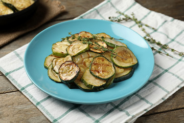 Plate with tasty grilled zucchini on wooden table