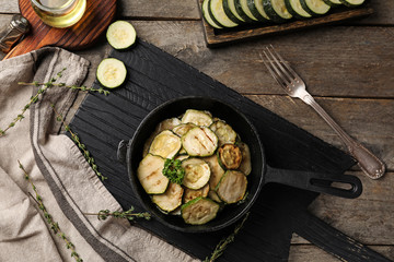 Pan with tasty grilled zucchini on wooden board