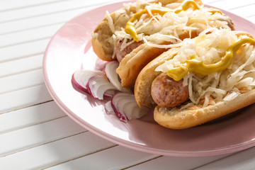 Plate with tasty hot dogs and sauerkraut on white wooden table