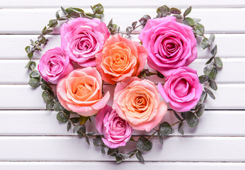 Heart made of beautiful flowers and leaves on white wooden background