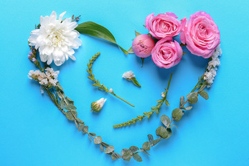 Heart made of beautiful flowers and leaves on color background