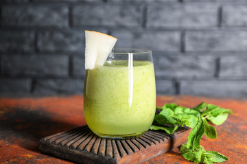 Glass of fresh melon smoothie on wooden board