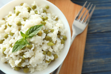 Bowl with tasty boiled rice and peas on board, closeup