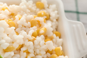 Bowl with tasty boiled rice and corn kernels, closeup