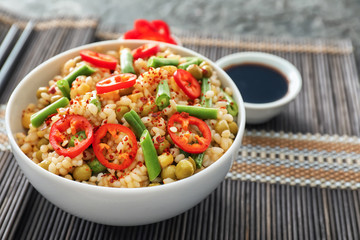 Bowl with tasty boiled rice and vegetables on table, closeup