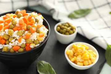 Bowl with tasty boiled rice and vegetables on slate plate, closeup