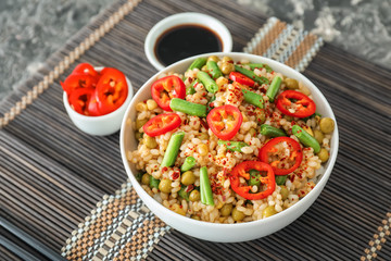 Bowl with tasty boiled rice and vegetables on table