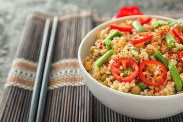 Bowl with tasty boiled rice and vegetables on table, closeup
