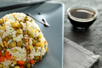 Plate with tasty boiled rice and vegetables on table, closeup