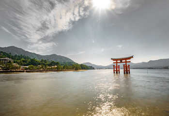 Torii gate, high tide and sun on top of the gray sky