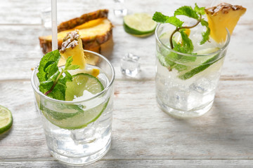 Glasses of tasty pineapple cocktail on light wooden table