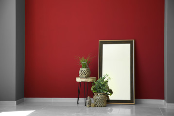 Big mirror, stand and houseplants near color wall