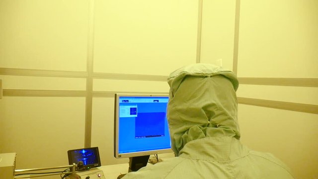 A pan of a scientist working on a big electrone microscope in the clean room.