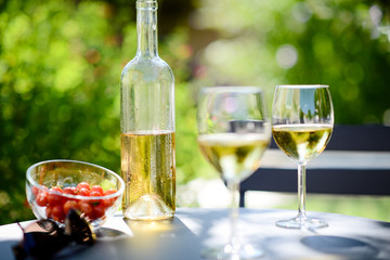 two glass of cool white wine with bottle outdoor in restaurant terrace during a sunny summer day