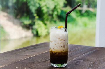 latte coffee and milk cold drink on the glass on wood table in the nature background