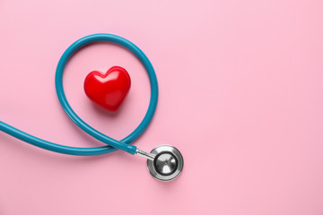 Medical stethoscope and red heart on color background. Cardiology concept