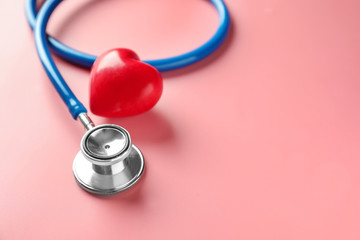 Medical stethoscope and red heart on color background. Cardiology concept