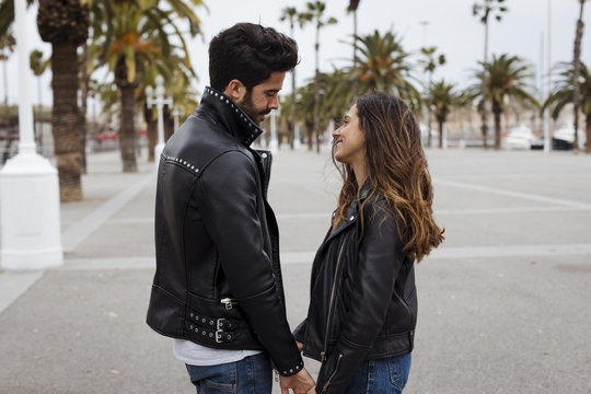 Spain, Barcelona, smiling young couple on promenade with palms