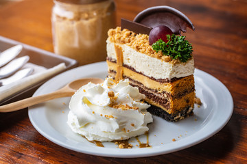 Chocolate cake and cream in white plate on wooden table.