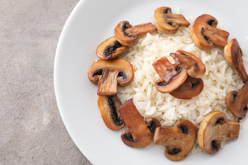 Plate with tasty boiled rice and mushrooms on light table