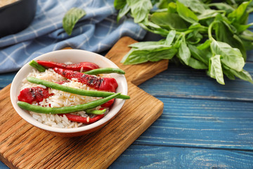 Plate with tasty boiled rice and vegetables on wooden table