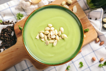 Bowl with tasty zucchini soup on wooden board