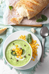 Tasty zucchini soup with corn in white bowl on table