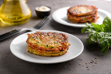 Plate with zucchini pancakes on grey table