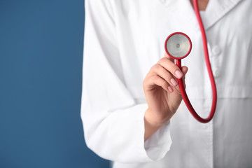 Doctor with medical stethoscope on color background, closeup