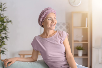 Happy woman after chemotherapy  sitting on sofa at home