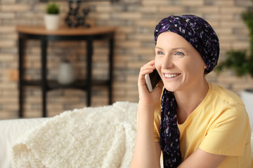 Woman after chemotherapy talking on mobile phone at home