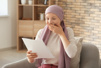 Happy woman after chemotherapy reading test results at home