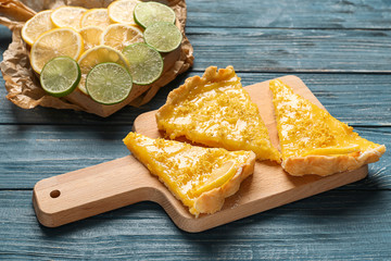 Board with pieces of delicious lemon pie on wooden table