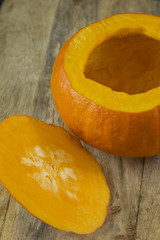 Pumpkin with cut top removed at wood board on dark background