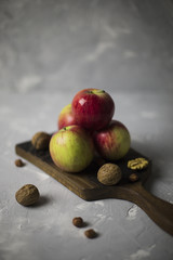 Composition with pink lady apples, walnut, hazelnut and leafs at beige napkin on gray background