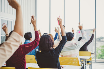 Group of business people raise hands up to agree with speaker in the meeting room seminar