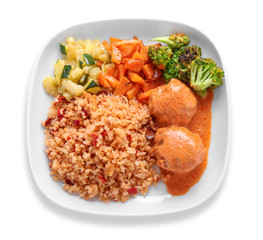 Tasty boiled rice with meatballs and vegetables on plate, isolated on white