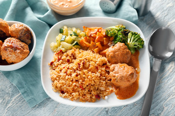 Tasty boiled rice with meatballs and vegetables on plate