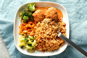 Tasty boiled rice with meatballs and vegetables on plate