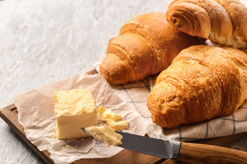 Tasty croissants and butter on light textured background