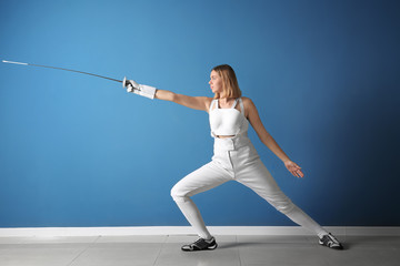Young female fencer against color wall