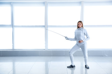 Young female fencer training in gym