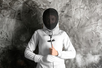 Young female fencer against grunge wall